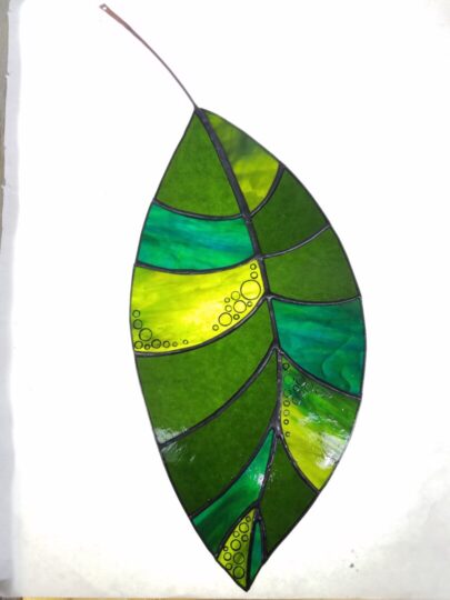 a delicate single leaf made of a variety of shades of green stained glass.