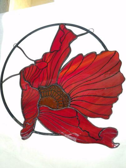 A red flower blowing in the wind, framed by a circular metal ring